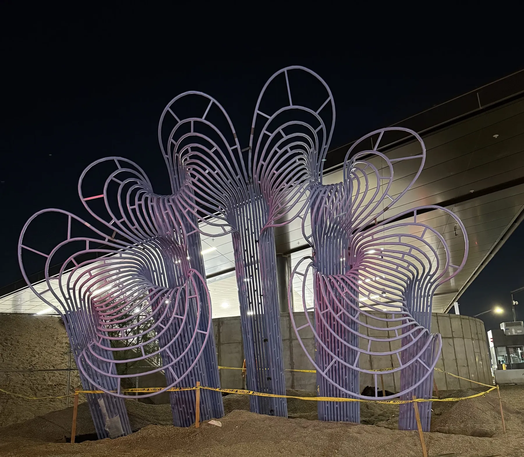 Tall looping metal forms at the Calexico border crossing, photographed at night during installation