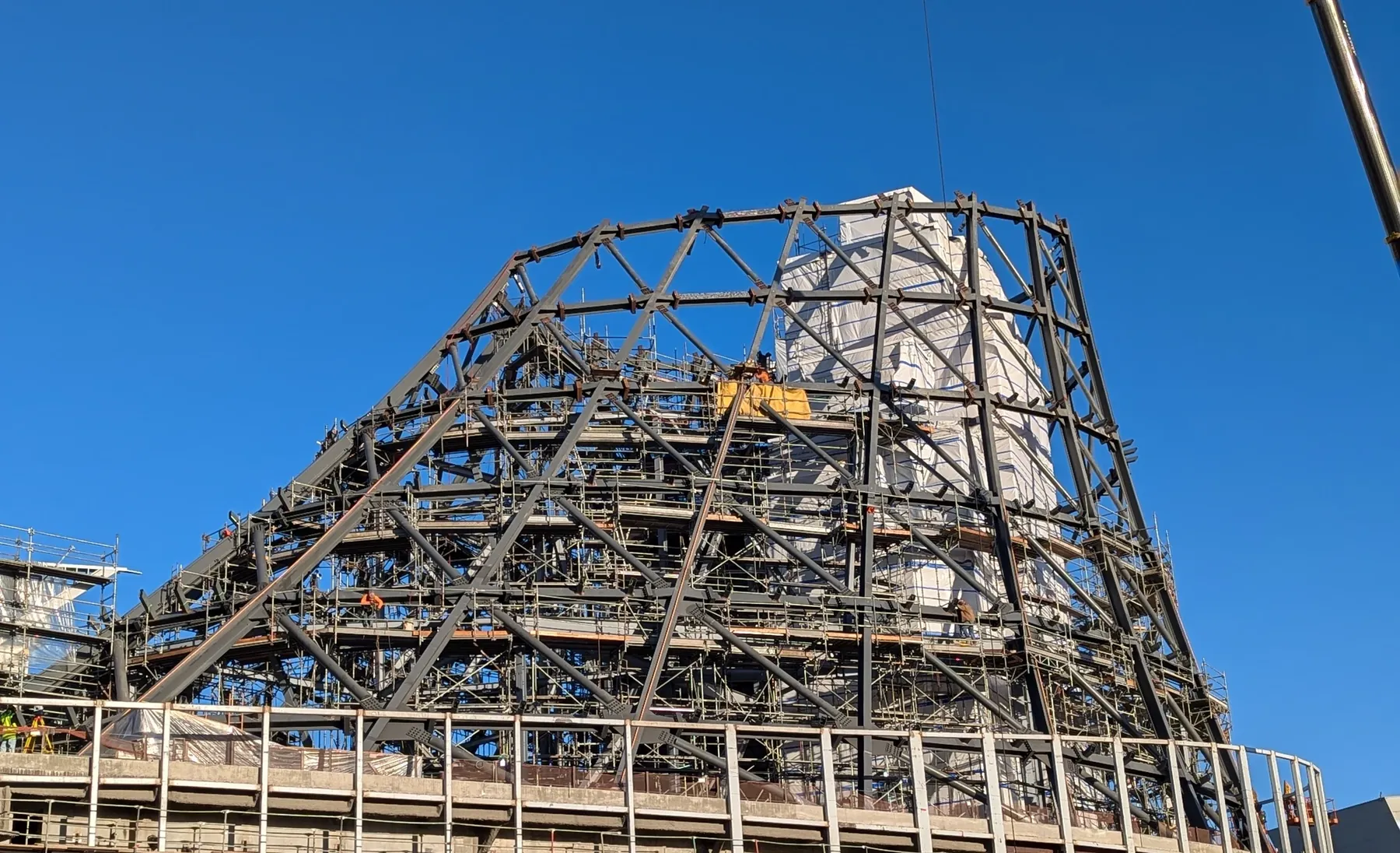 Exposed steel framing and scaffolding at the California Science Center beneath a clear blue sky