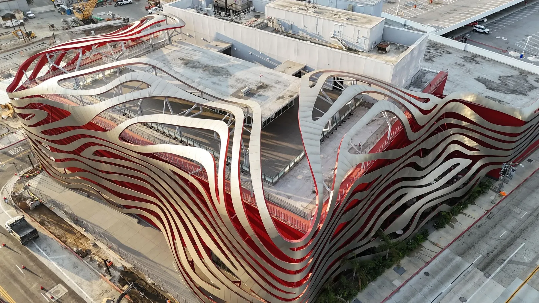 Aerial view of silver ribbons wrapping the red exterior of the Petersen Automotive Museum during construction