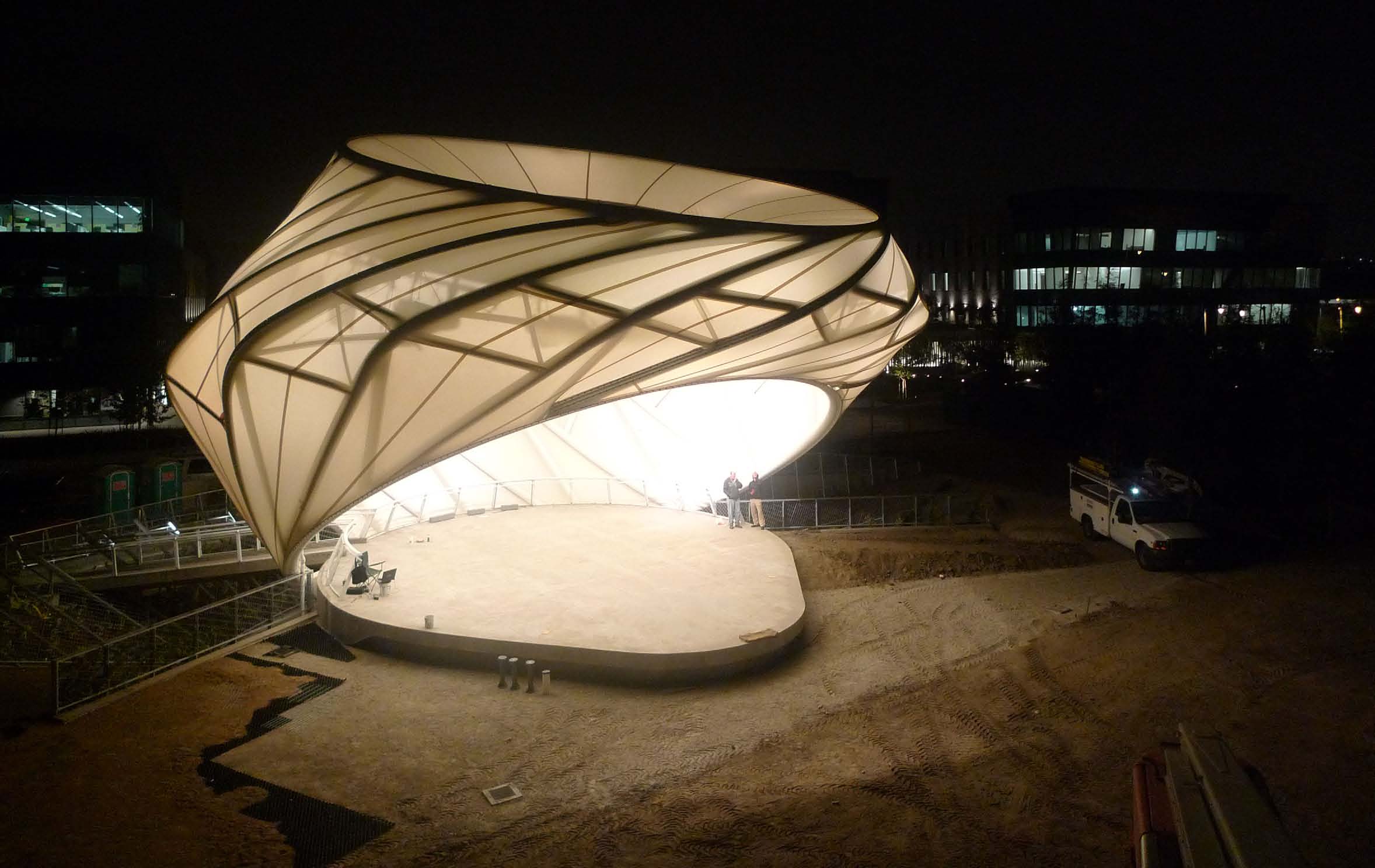 The illuminated curved structure of the Playa Vista Bandshell at night